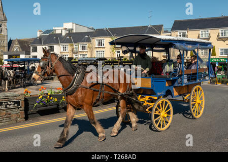 Killarney popular tourist activity as horse drawn carriage or jaunting car with tourists in the streets on bright sunny day in Killarney Ireland Stock Photo