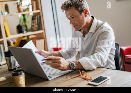Focused businessman using laptop at desk Stock Photo