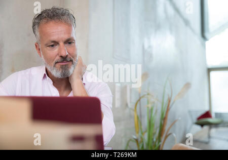 Businessman in a loft using laptop Stock Photo