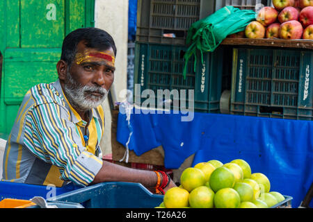 A bearded man with a tilaka in a street market selling lemons and fruit Stock Photo