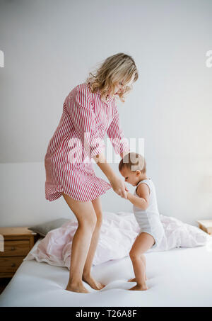 Mother playing with toddler son on bed at home Stock Photo
