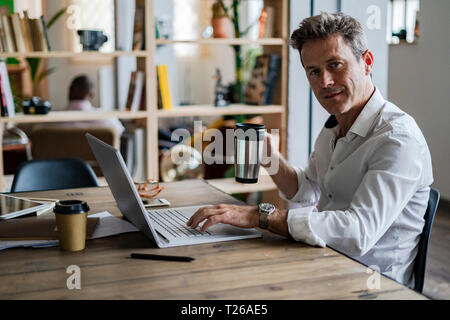 Portrait of businessman using laptop at desk Stock Photo