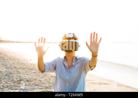 Thailand, woman using Virtual Reality Glasses on the beach Stock Photo