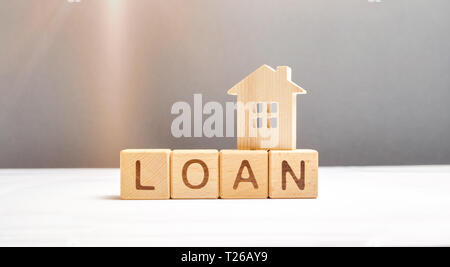 Wooden figure of the house and the cubes with the inscription loan. Mortgage programs and the purchase of affordable housing for young families and ci Stock Photo