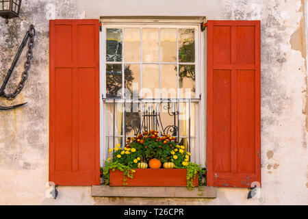 Exterior window of historic colonial home with flower box and red shutters Stock Photo