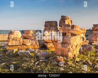 Ruins and parts of ancient columns, capitels and bases with Greek and Christian symbols at sunset Stock Photo