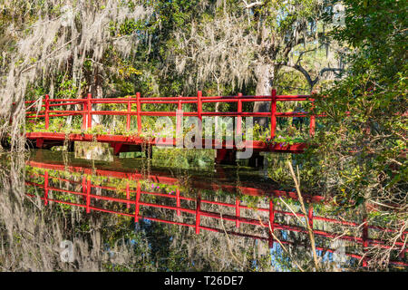 Reflection of red wooden bridge over a lake in Magnolia Plantation in Charleston, South Carolina Stock Photo