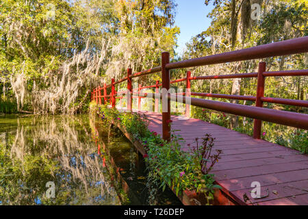 Reflection of red wooden bridge over a lake in Magnolia Plantation in Charleston, South Carolina Stock Photo