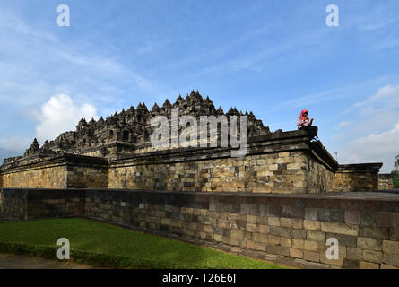 BOROBUDUR, INDONESIA- 08.23.2017. Young indonesian woman using smartphone in the temple of Borobudur. Stock Photo