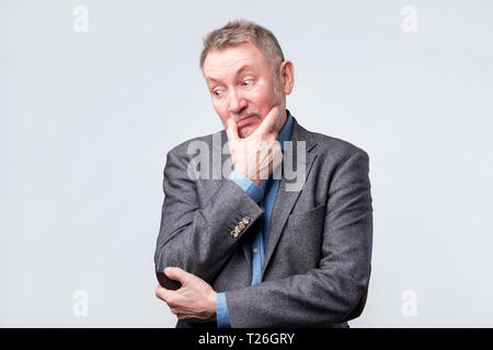 Handsome middle age man in suit has doubt expression, is confused, uncertain in future Stock Photo