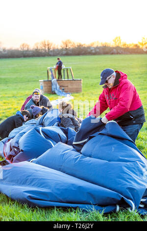 Hot air ballooning, Bristol. After an evening flight, the balloon once deflated needs to be packed away by the passengers. Stock Photo