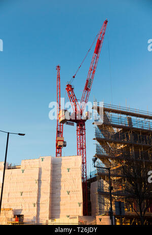 Construction site with 2 / two luffing jib tower cranes at work / working on what will be Twickenham Gateway mainline railway station. London. UK. Stock Photo