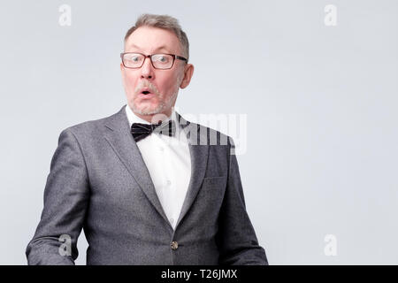 Surprised senior european man in glasses and suit looking at camera. He is shocked with news. Stock Photo