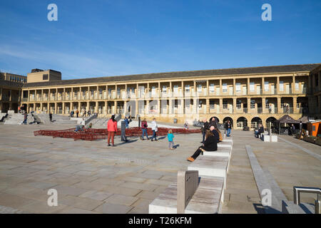 View looking across the open square towards the North Wall of the quadrangle of restored The Piece Hall. Sunny / sun & blue sky. The sunlit Northwall is in the background. Halifax, West Yorkshire, England UK Stock Photo