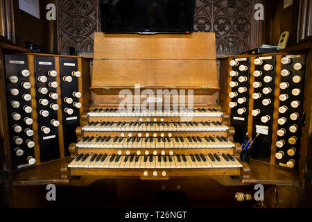Organ (musical instrument ) and its keys / keyboard in Halifax Minster. The organ stops are visible on either side. West Yorkshire. UK. It was made by Harrison and Harrison of Durham UK Stock Photo