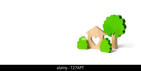 A house with a heart and wooden figures of trees with bushes on an isolated background. love nest. Acquisition of affordable housing in a mortgage or  Stock Photo