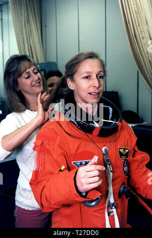 STS-81 Mission Specialist Marsha S. Ivins gets a helping hand from a suit technician as she prepares to don the helmet of her launch/entry suit in the suitup room of the Operations and Checkout (O&C) Building ca. 1997 Stock Photo