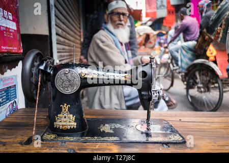 Old Singer sewing machine and elder men in the blurred background. Geneva Camp, stranded Pakistanis enclave in Dhaka, Bangladesh. Stock Photo