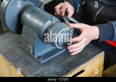knife sharpening machine and master. Grinding machine. grinding knife using abrasive stone Stock Photo