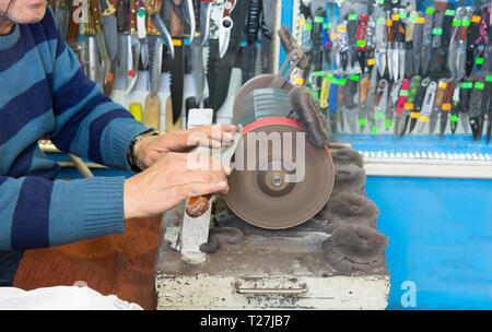knife sharpening machine and master. Grinding machine. grinding knife using abrasive stone Stock Photo