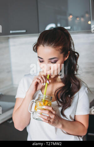 The beautiful asian girl young woman drinking lemon water from glass jar in kitchen Stock Photo