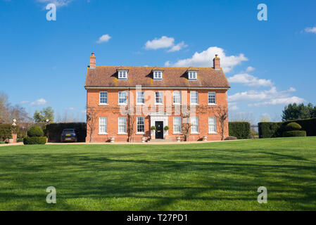 Elegant English Country Manor mansion house Grade 2 listed Victorian period property in red brick. Front view with large garden and green lawn Stock Photo