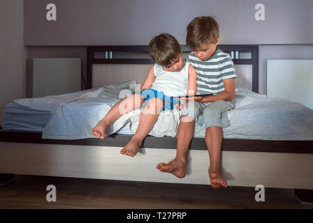 Children and gadgets. Two boys with tablet on the knees. Home schooling concept. Preschooling background. Home activities. Recreations background Stock Photo