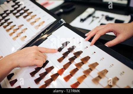 Close-up of woman choosing dark color hair from palette on white background Stock Photo
