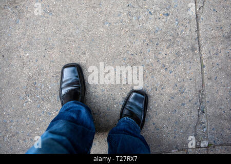 Looking down at a man's shoes and blue jeans slacks Stock Photo