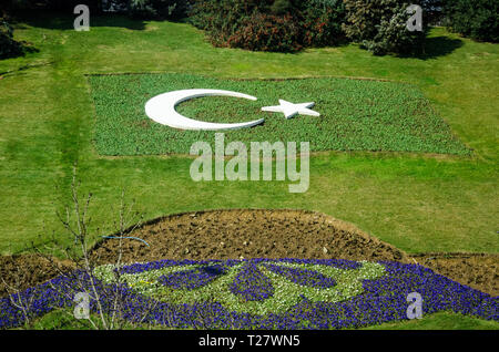 one of many beautiful arranged parks in Istanbul,showing star and  half moon in white on grass with flowers decoration.Turkish symbol of national flag Stock Photo