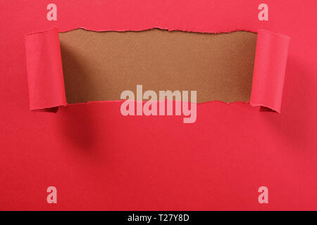 Torn red paper strip curled top edge revealing brown background Stock Photo