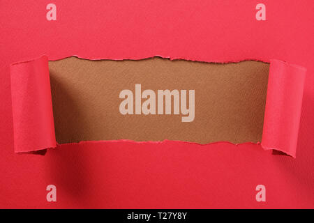 Torn red paper strip curled edge revealing center brown background Stock Photo