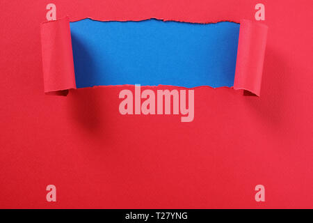 Torn red paper strip curled edge revealing top blue background Stock Photo