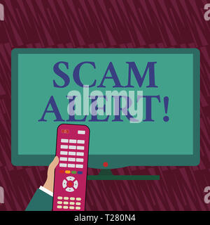 Text sign showing Scam Alert. Business photo showcasing illegal trick usually with purpose of getting money from showing Hand Holding Computer Remote  Stock Photo