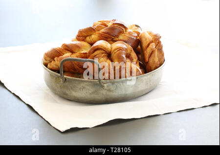 Freshly baked cinnamon buns. Cinnamon roll pastries in a pile in an antique metal tray with white background Stock Photo