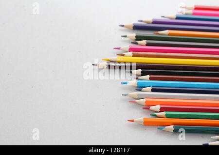 Color pencils for schoolchildren and students. Pencils are scattered on a white table and stand in a glass. Pencils for office workers. Stock Photo