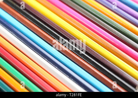 Color pencils for schoolchildren and students. Pencils are scattered on a white table and stand in a glass. Pencils for office workers. Stock Photo