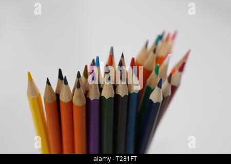 Color pencils for schoolchildren and students. Pencils are scattered on a white table and stand in a glass. Pencils for office workers. Stock Photo