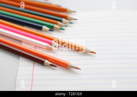 Color pencils for schoolchildren and students. Pencils are scattered on a white table and stand in a glass. Pencils for office workers. Stock Photo