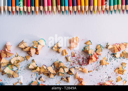 Row of colored sharpened crayons and colored shavings on paper background Stock Photo
