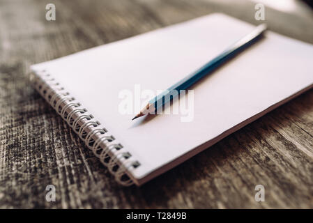 A pencil and a notebook on wooden surface close up. Stock Photo