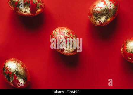 Five golden colored and decorated with sparkles Easter eggs on red background. Happy Easter greeting card. Easter background. Stock Photo