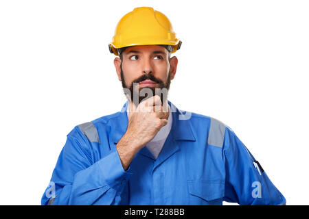 Thoughtful bearded middle age man in hard hat, foreman or repairman in the helmet touching his beard and thinking thoughtful with smart face, expressi Stock Photo