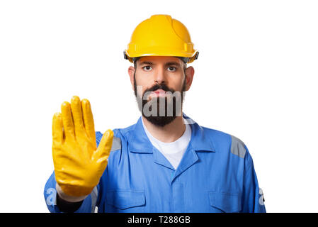 Middle age bearded handsome workman with yellow helmet and uniform making stop gesture with his hand denying a situation that thinks wrong. Isolated o Stock Photo