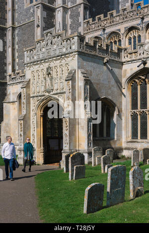 Church porch Suffolk, view of a tourist couple emerging from the late medieval (1525) great porch of the Church of St Peter & St Paul in Lavenham, UK. Stock Photo