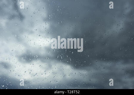 nimbostratus clouds behind a window with drops of rain over it Stock Photo