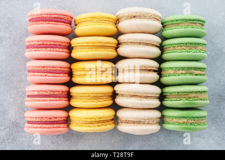 Rows of various colorful french macarons on a gray background. Stock Photo