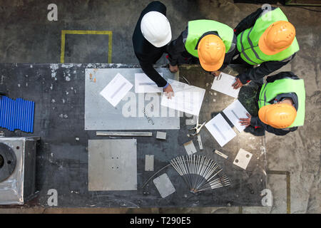 Workers and manager in safety helmets working with documents at factory table Stock Photo