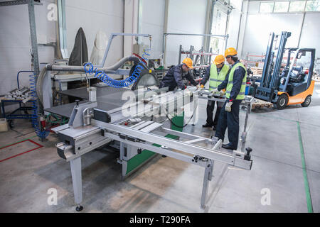 Team of three workers in CNC factory working at machine Stock Photo