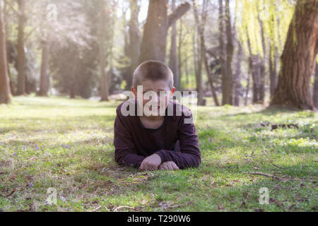 Smiling young boy lying on grass in the park Stock Photo
